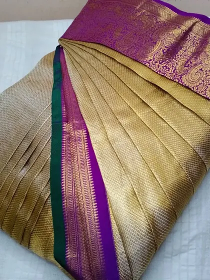 A gold tissue saree with a purple and green border.