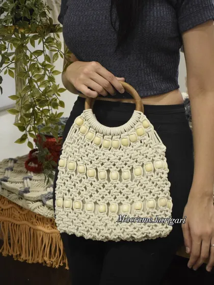 This macramé tote bag features a beautiful wooden handle and is embellished with beads for a sophisticated look. It’s a spacious and stylish bag, perfect for daily use.