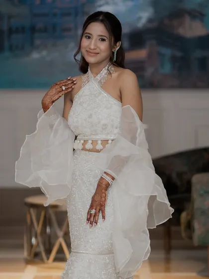The full view of Kaaya's stunning white outfit. The makeup is kept minimal and glowing to balance the dramatic sleeves.