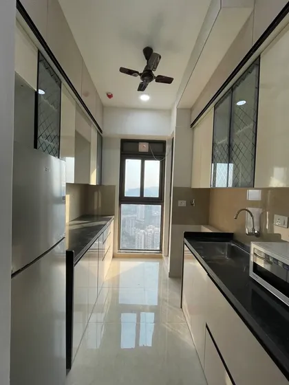 A full view of a galley kitchen in Kanjurmarg, designed with neutral tones and black accents for a timeless and sophisticated look.