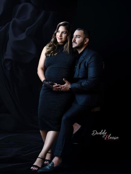 An intimate pose from a couple's maternity session. The dark clothing and background keep the focus entirely on their connection and the baby bump they are cradling.