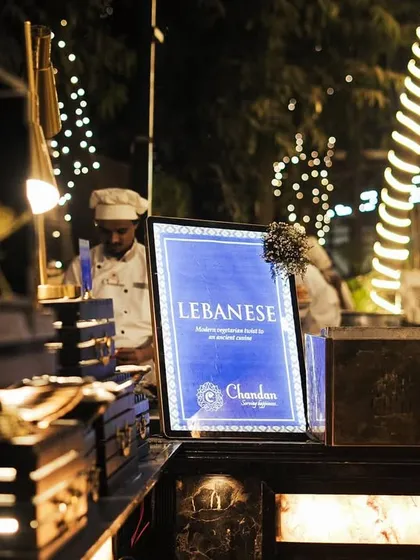 The sign for our Lebanese station, set against a beautifully lit backdrop at an evening event. I offer a range of authentic Middle Eastern delicacies.