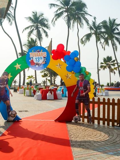 A grand entrance for a sports party, with a red carpet and cutouts of famous football players.
