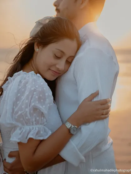 A soft and tender moment during a sunset beach shoot. The bride rests her head on the groom's chest, and the warm, golden light creates a beautifully romantic and peaceful atmosphere.