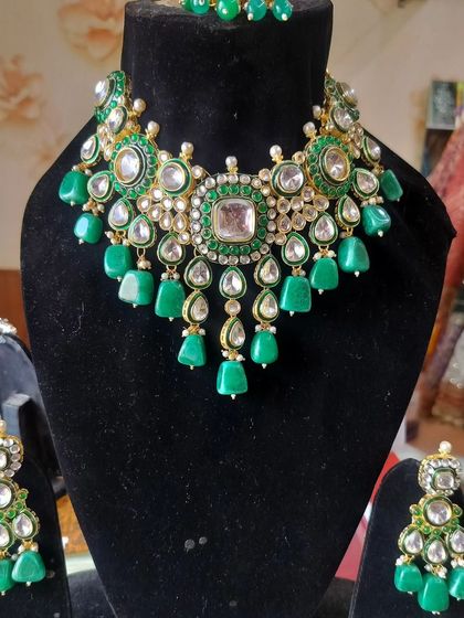 A heavy Kundan necklace set with large emerald green stones and pearl drops, a perfect statement piece.