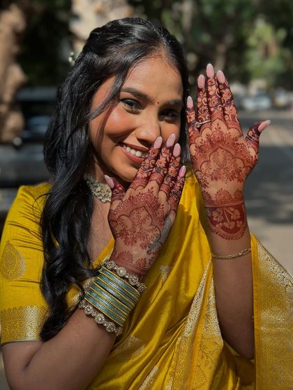 A radiant client showing off her gorgeous mehendi stain on her engagement day. The deep color looks stunning against her yellow saree.