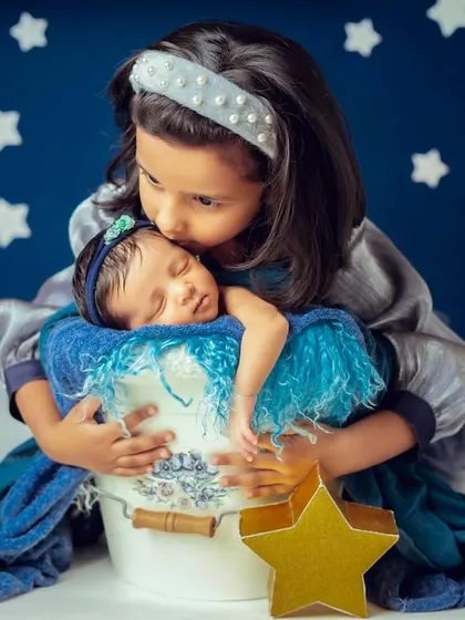 The beginning of a lifelong bond. There is nothing more precious than a big sister's first moments with her newborn sibling, captured here in a themed newborn photoshoot.