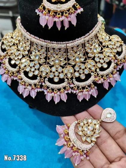 A close-up of a pink choker with a lotus and moon motif. This is a unique and beautiful rental piece for a special occasion.