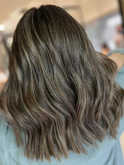 This is a great example of a warm-to-cool hair color transformation. I used cool-toned highlights to neutralize warmth and gave her a textured cut for a completely refreshed style.