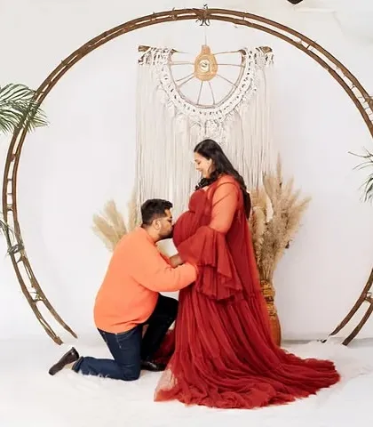A stylish maternity session in my Jaipur studio, featuring a popular boho theme with natural textures and soft lighting. The father-to-be kisses the baby bump, creating a tender moment.