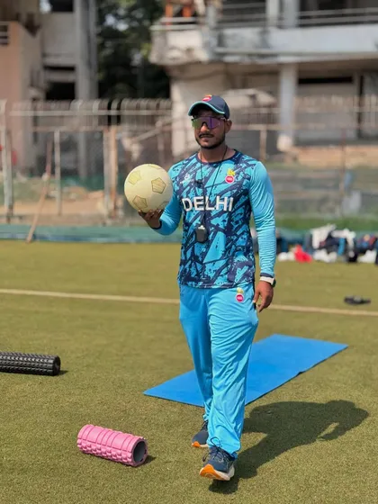 Holding a football, with my foam rollers and yoga mat nearby. A holistic approach to fitness is key.