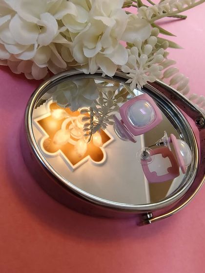 Another creative shot of the pink enamel square earrings, showing their reflection and unique design.