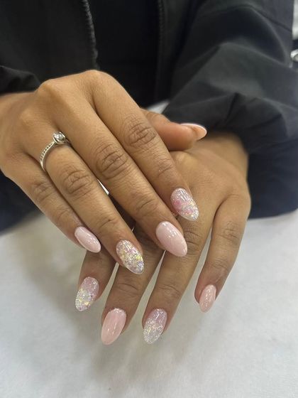 A soft and elegant almond-shaped nail set. The design features a delicate pink base with a sparkling glitter fade, creating a sophisticated and eye-catching look suitable for any occasion.