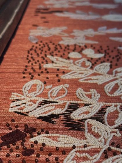 A close-up of the handcrafted embroidered wallpaper. Every inch is detailed with floral motifs, delicate beading, and intricate stitching, showcasing the level of artisanal craft we integrate into our projects to create truly unique surfaces.