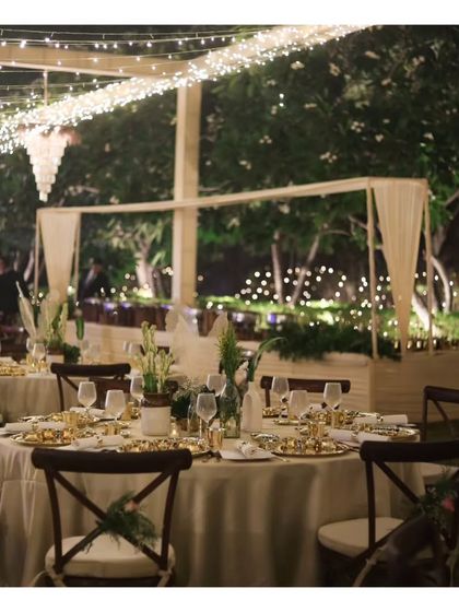 An outdoor sit down dinner setup under a canopy of fairy lights. This enchanting setting demonstrates our versatility in transforming any space, from a banquet hall to a garden, into a magical dining venue.