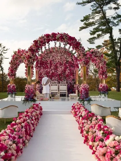 The wedding mandap is the heart of the ceremony, and we design it to be a showpiece. This stunning outdoor setup features a lush floral arch in shades of pink and a pristine white aisle, creating a romantic and picturesque setting for the vows.