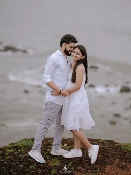 A sweet embrace on the edge of a coastal cliff. This pose beautifully captures the couple's closeness against the vastness of the sea.