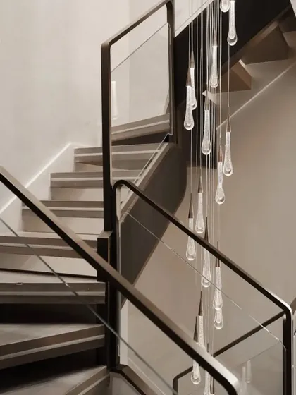 The dramatic teardrop chandelier cascades down the stairwell, serving as a stunning piece of functional art. This highlights our expertise in selecting and placing statement lighting to elevate a space.