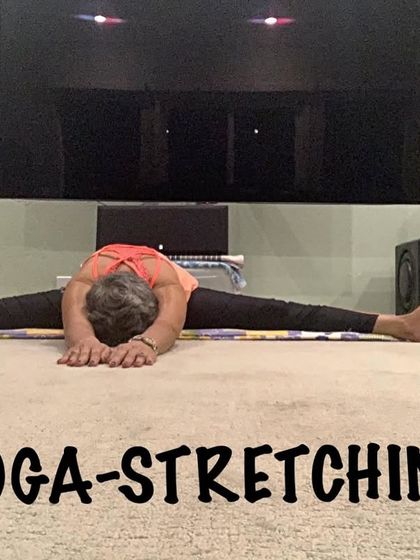 A full forward bend in the center split, a posture that requires significant flexibility. I guide students through preparatory poses for this deep stretch.