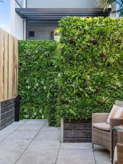 This cozy patio setup shows how artificial vertical gardens can provide privacy and a sense of enclosure. The dense green wall creates a secluded retreat, perfect for city living.