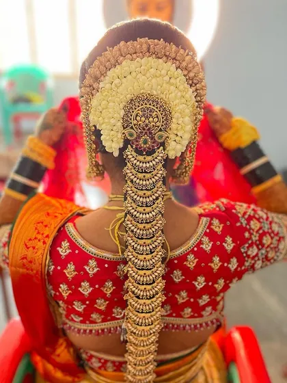 A stunningly ornate Muhurtham hairstyle, featuring a full Jadde Billai set and a beautiful arrangement of fresh flowers.