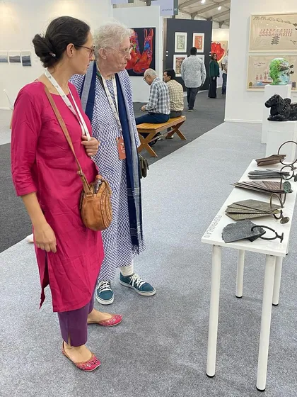 Two visitors examining the intricate copper sculptures by Pushpamala N.