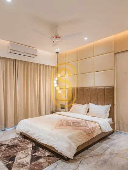 This serene bedroom is designed with a neutral color palette, featuring a tufted beige wall panel behind the bed. The modern cascading light fixture adds a touch of contemporary elegance.