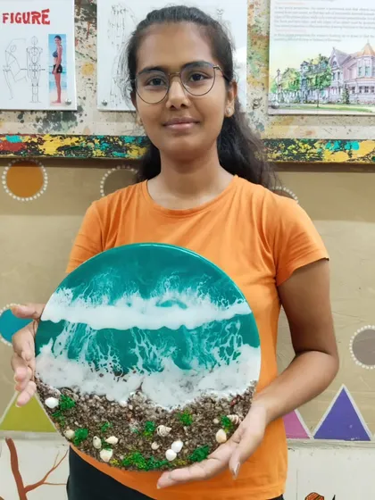 A proud student holding her completed resin beach art. Our classes provide the guidance needed to turn a creative idea into a tangible, beautiful object.