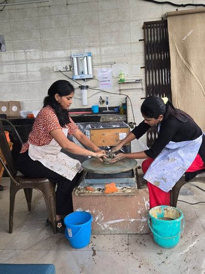 Two participants work side-by-side on their pottery wheels inside the studio. It's a space for individual focus within a shared creative environment.