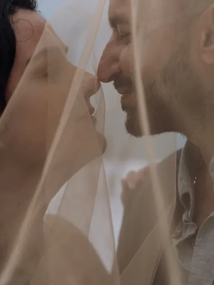 A creative and intimate shot of the couple seen through a translucent veil, creating a soft, dreamy, and romantic effect.