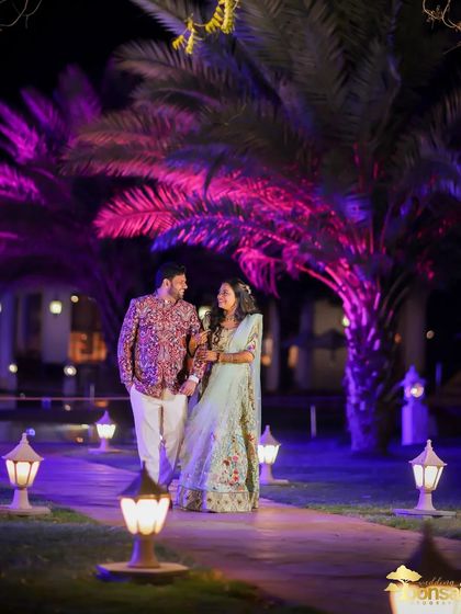 A beautiful night shot from an engagement ceremony, with dramatic purple lighting on the palm trees creating a magical atmosphere.