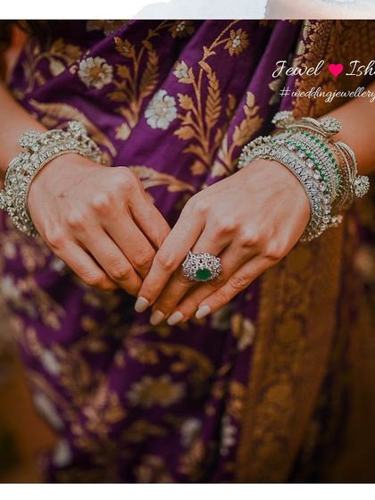 A focus on the hands, adorned with beautiful diamond and emerald bangles and a statement ring. Accessorizing your hands is key to completing your bridal look.