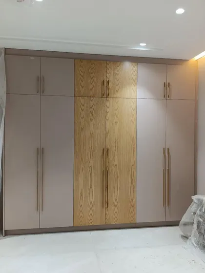 This modern wardrobe design features a two-tone finish, combining a light wood grain with a soft neutral color. The sleek, minimalist handles and clean lines make it a perfect fit for a contemporary bedroom.
