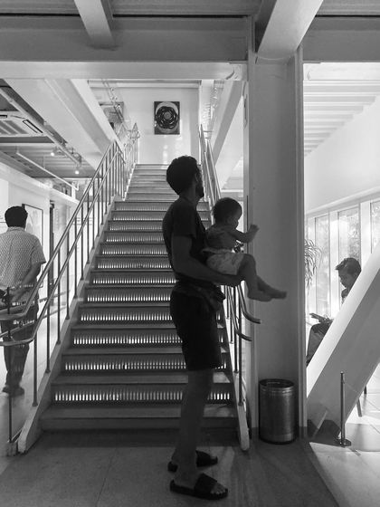 A visitor with a small child enjoys the view from the main staircase at the Museum of Art and Photography (MAP). The building's open and light-filled circulation spaces are designed to be welcoming for everyone.