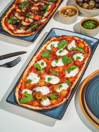 A top-down shot of a rectangular Margherita pizza with fresh burrata, styled with hard light and sharp shadows. This clean, graphic approach is modern and perfect for a digital menu.