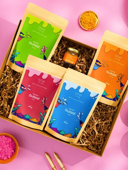 Another angle of the Holi gift box, this time on a bright pink background. This top-down shot clearly displays all the contents of the box in a fun and eye-catching way, perfect for social media announcements.