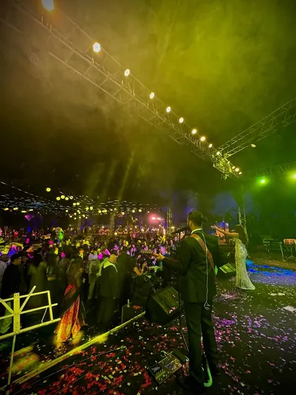 A wide shot from the stage, looking out at a massive wedding crowd. The combination of stage lighting, smoke effects, and a high-energy audience creates a truly epic party atmosphere.