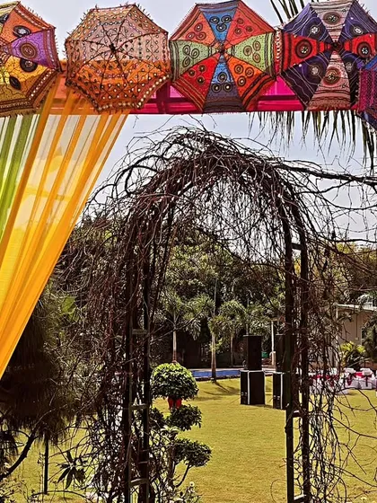A creative entrance for a Holi party or Mehandi function, using colourful Rajasthani umbrellas and bright drapes.