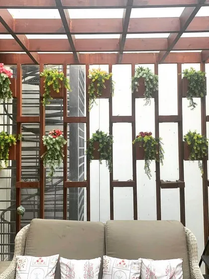 My work goes beyond standard green walls. Here, I designed a custom wooden slat partition with integrated hanging planters to create a stylish and green separation for a cozy seating area.