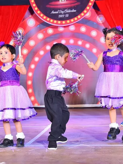 Young performers full of energy on stage in two-tone purple and lilac dresses, complete with matching accessories for their annual day celebration.