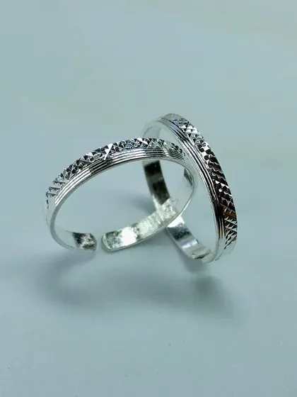 Another view of the classic etched silver toe rings, shown on a plain background to highlight their pattern.