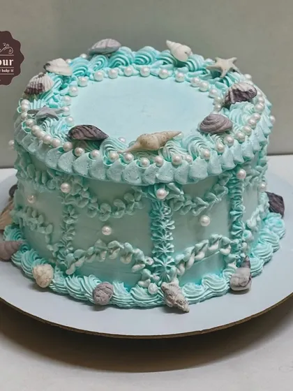 An underwater theme cake for a teenager. This cake features delicate piping work and edible seashells, creating a beautiful vintage-style ocean design.