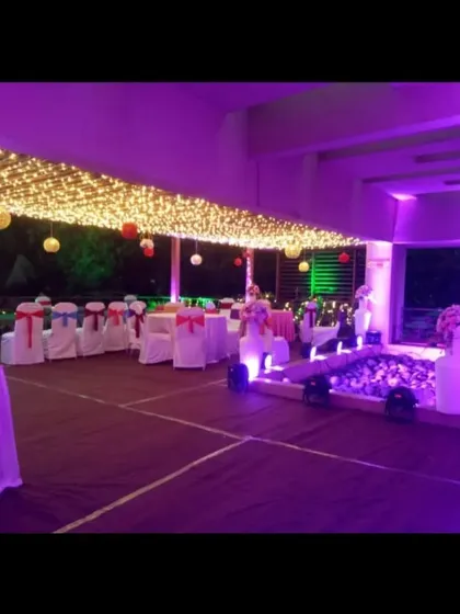 A wide view of an outdoor reception area. The space is defined by a ceiling of fairy lights and includes guest dining tables, creating a beautiful open-air hall for the celebration.