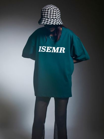A moody, atmospheric shot of a model in a bucket hat and oversized tee. The obscured face creates a sense of mystery and coolness, focusing attention on the overall style.