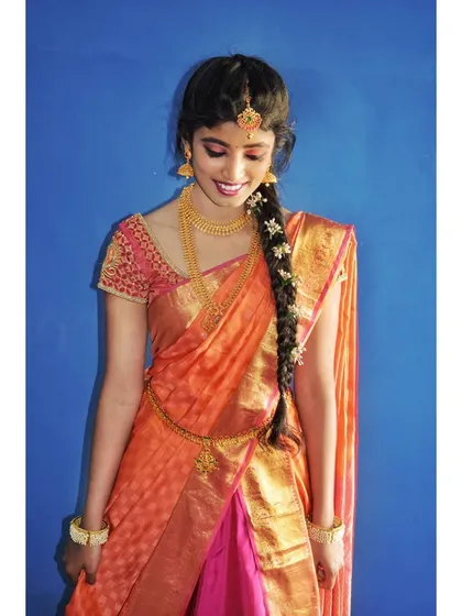 This full-length shot showcases the complete traditional attire. The makeup, hair, and half-saree draping all work together to create a graceful and festive look.