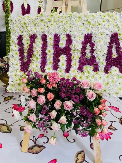 A personalized floral name board is a beautiful way to welcome a new baby. For Vihaa's naming ceremony, we crafted her name using deep purple chrysanthemums set against a bed of white flowers, with a fresh rose bouquet at the base.