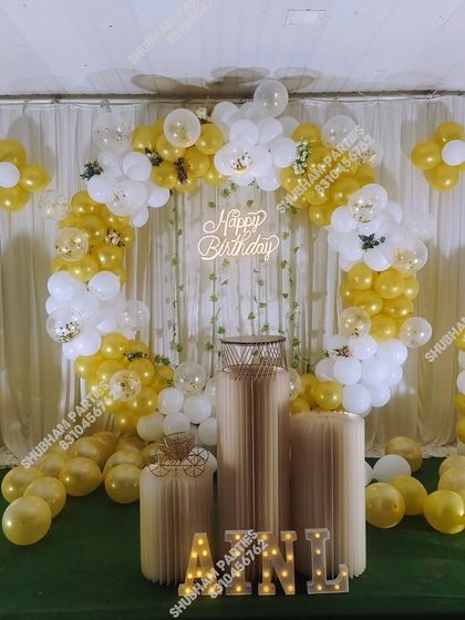 A beautiful gold and white balloon arch with a neon sign and marquee letters, set up on a green turf.