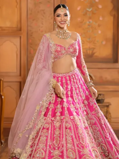 A full-length shot capturing the vibrant energy of the bridal look. The long, flowing gajra braid adds a traditional yet dramatic flair to the modern pink lehenga.