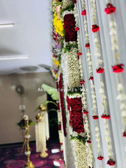 A close-up view of the floral details on a naming ceremony backdrop. This image shows the intricate work of jasmine and rose garlands against a clean white curtain.