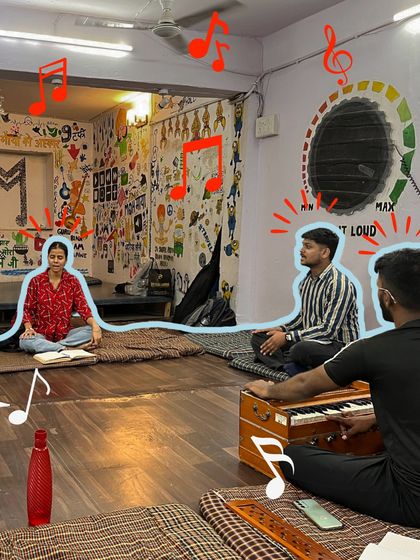An instructor plays the harmonium while students practice their vocals. The blue line connecting them symbolizes the harmonious connection created through music.